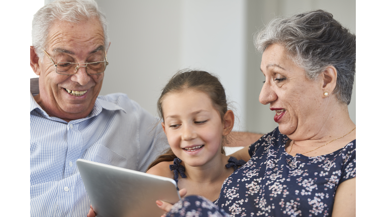 Little girl using tablet with grandparents