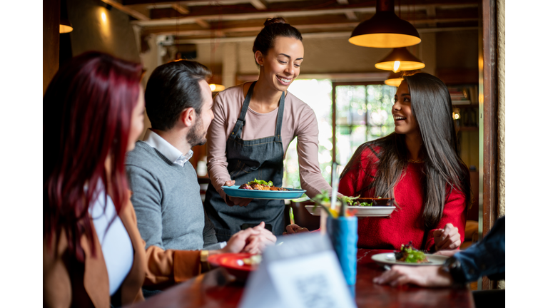 Waitress serving food to a group of customers at a restaurant