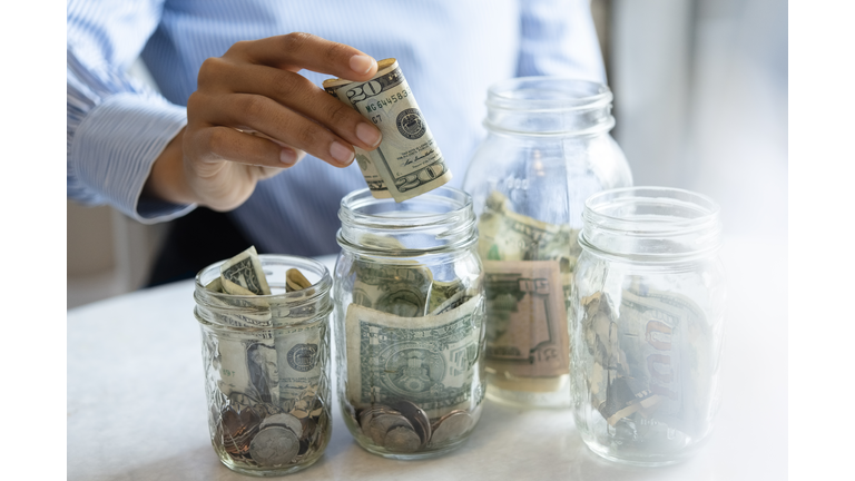 Hand of woman putting money in jar