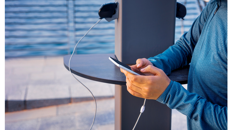 Female charging phone on a public charger