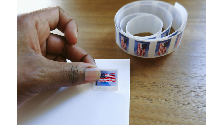 Woman Places Postage Stamp on Envelope