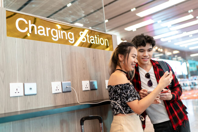 Young Asian couple enjoying free phone charge sharing at the airport