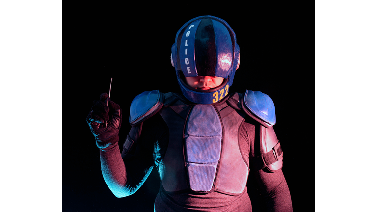 Cyberpunk concept, world of the future. Police officer in the dark, half-human, bionic cyborg holds his hand with a remote control from a bomb explosive. The stand looks into the camera in the dark. Science fiction scene, fantasy, science.