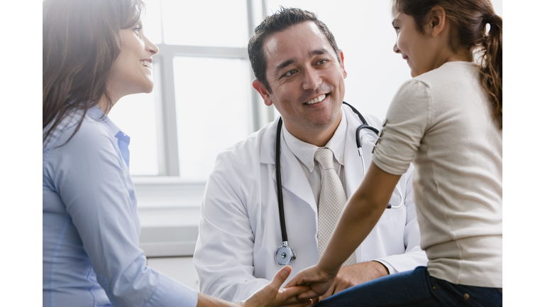 Doctor talking to girl and her mother in examination room