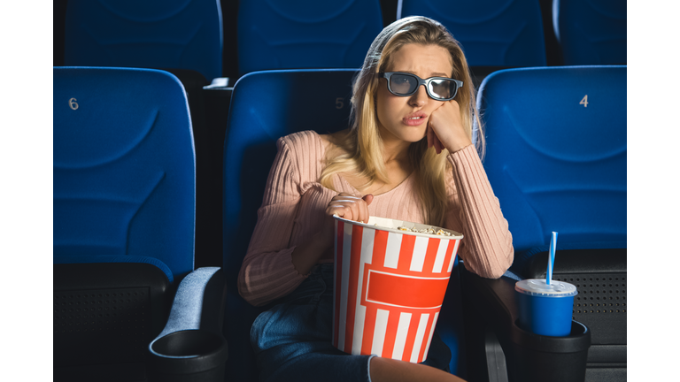 portrait of bored woman in 3d glasses with popcorn watching film alone in cinema