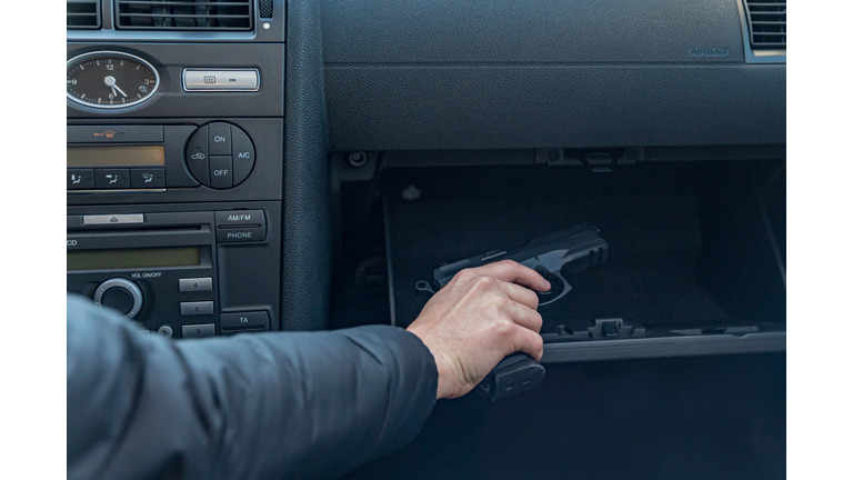 Close-Up Of Man Holding Gun In Car