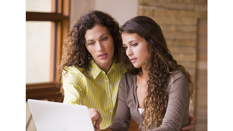 Mixed race mother and daughter using laptop together