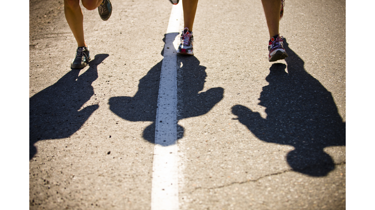 Shadows of group running on empty roadway.