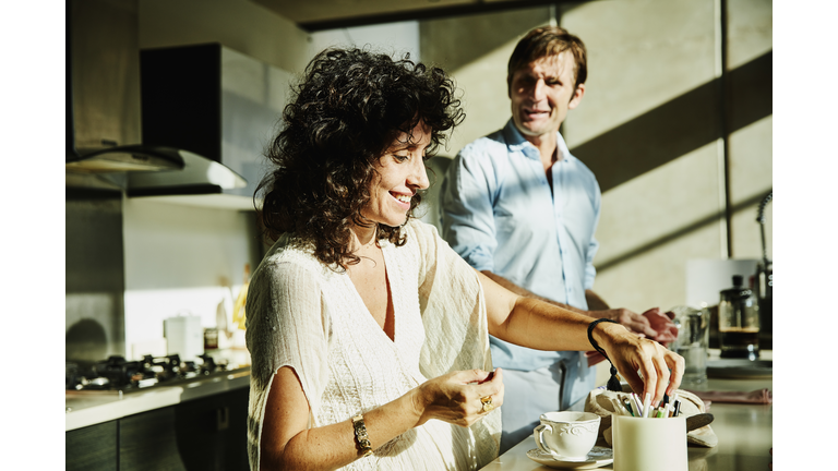 Smiling wife in discussion with husband while sitting in kitchen