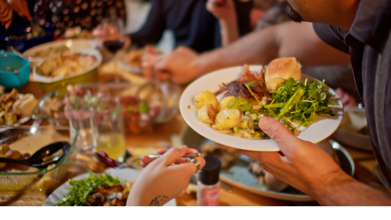 Man Serving Himself at Friendsgiving Potluck Dinner