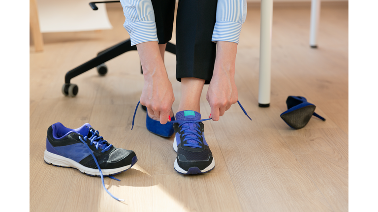 Woman changing high heels, office shoes after working day while sitting on the chair, ready to take a walk or run