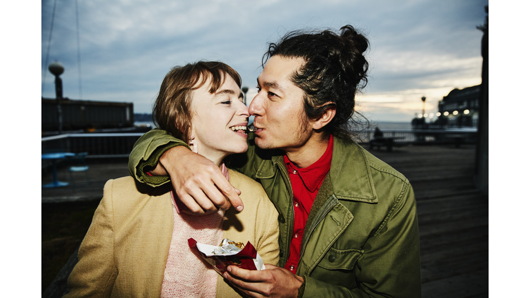 Smiling couple sharing piece of chocolate while on date