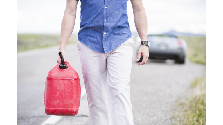 Caucasian man carrying gas on street