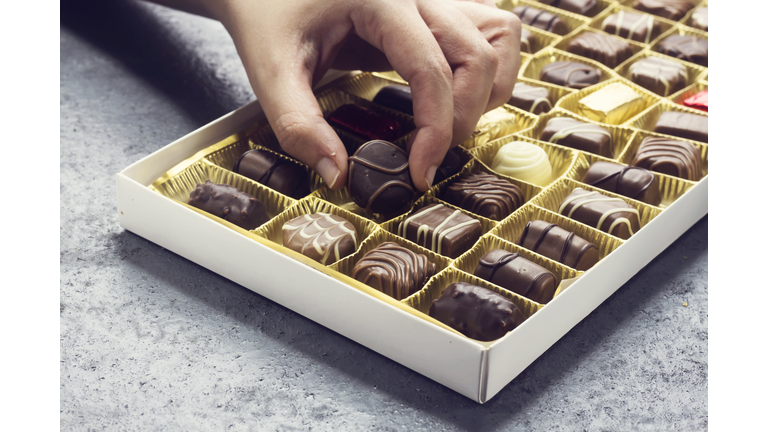 woman hand holding a chocolate piece from various type in  box for valentine's day