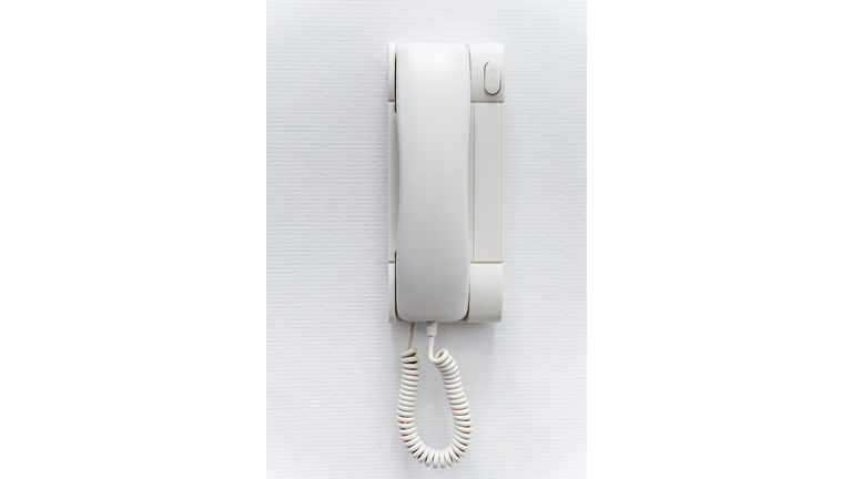 Close-Up Of Telephone Attached On White Wall