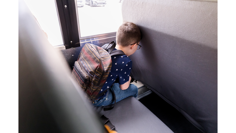 After hard day, young boy leans head on bus seat