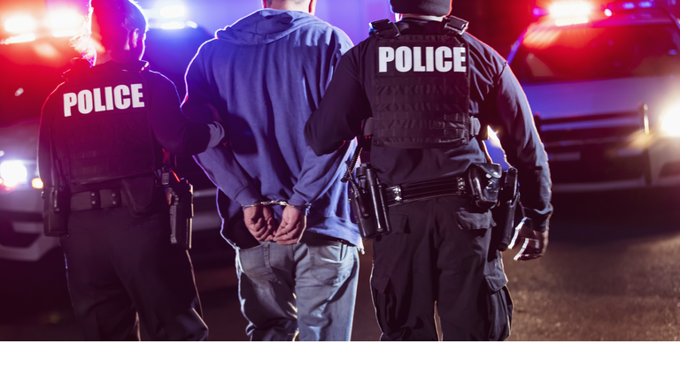 Handcuffed suspect being arrested by police at night