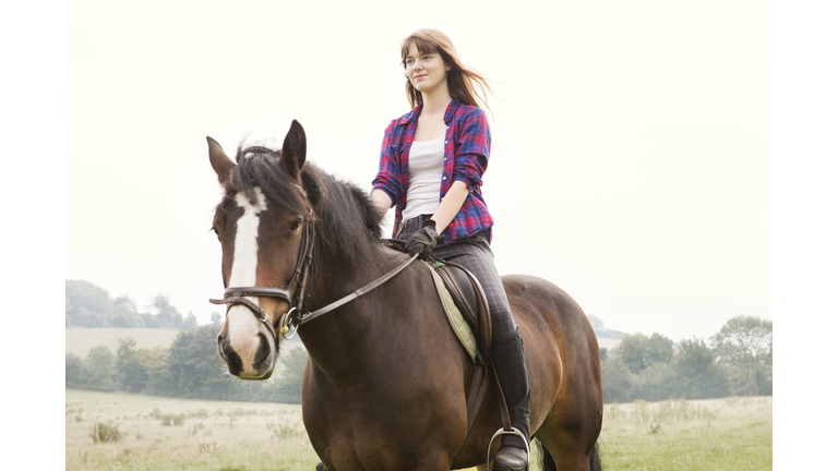 Young woman horseriding in hils and fields.
