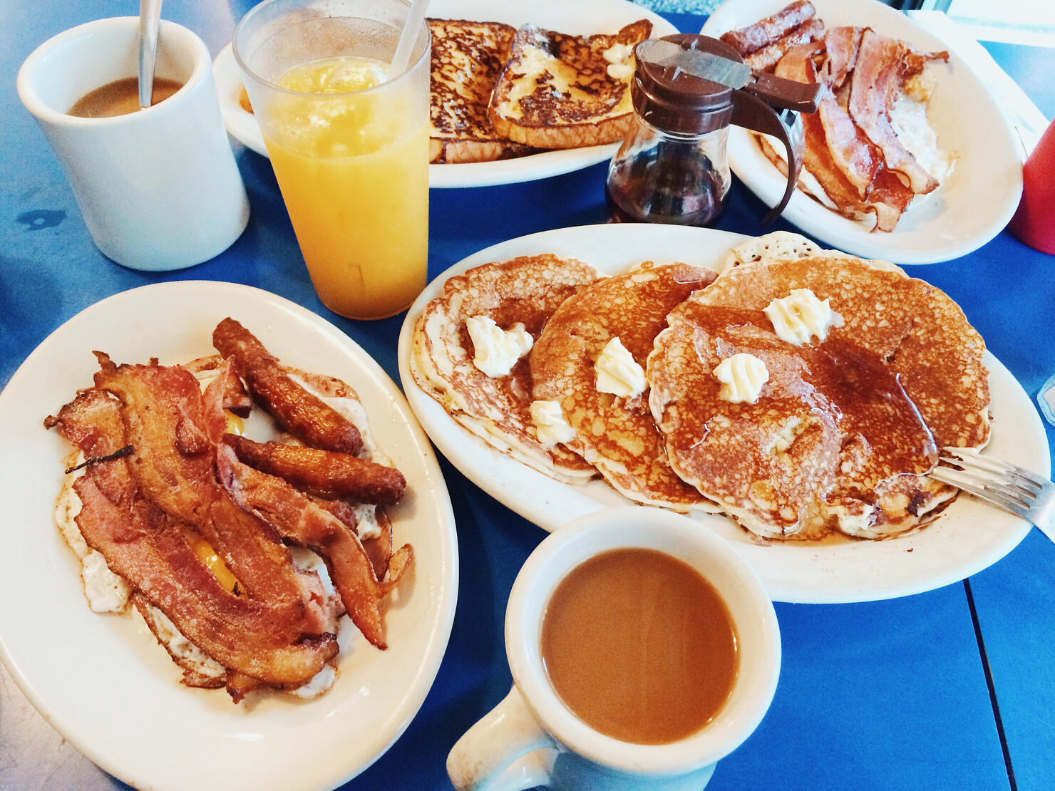 Classic American breakfast with fried eggs, bacon, pancakes, maple syrup and coffee served in a diner