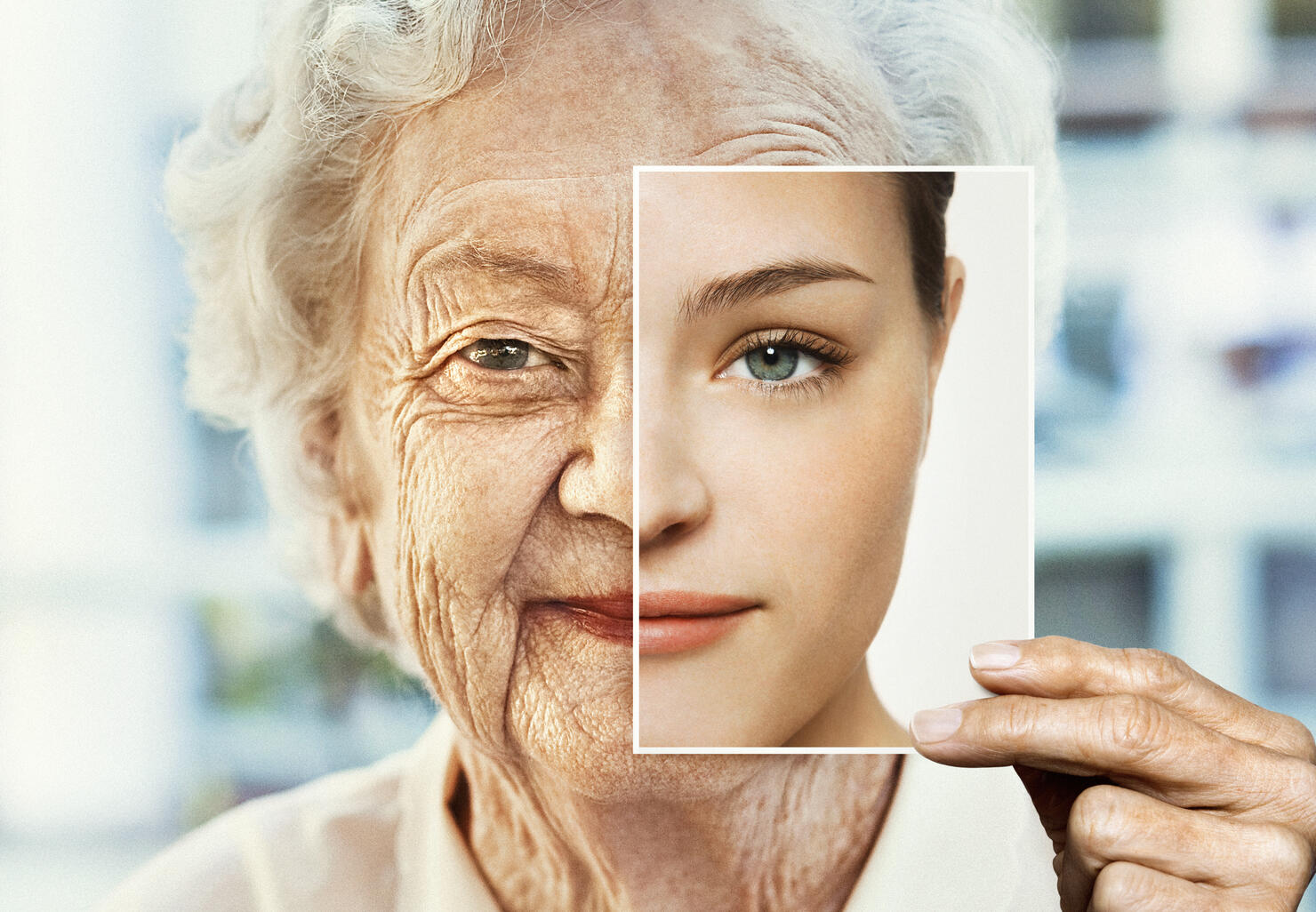 Portrait of woman holding younger photo of herself