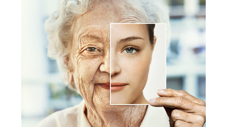 Portrait of woman holding younger photo of herself