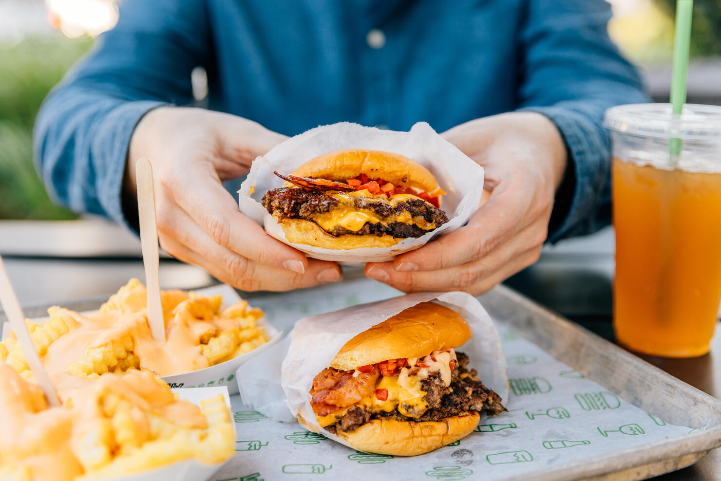 Man eating cheeseburger and cheese fries at fast food joint