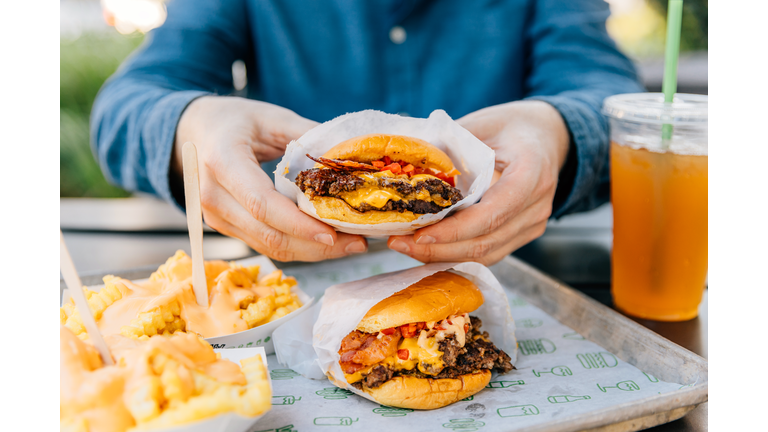 Man eating cheeseburger and cheese fries at fast food joint