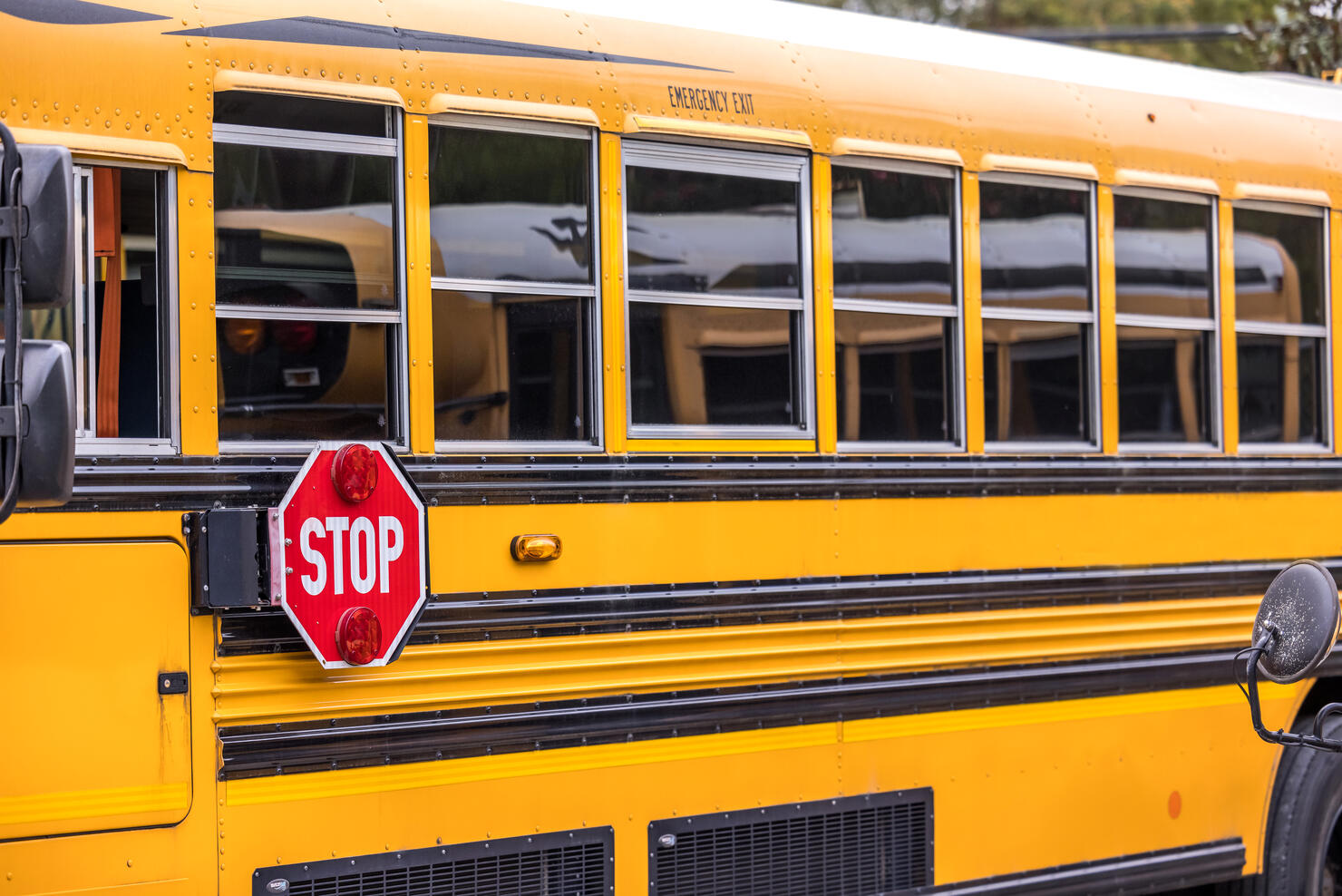 A close up of a yellow orange school bus with a red stop sign for back to school