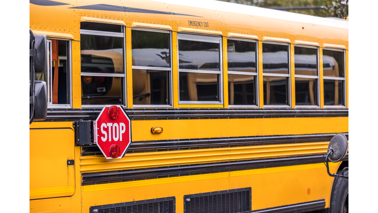 A close up of a yellow orange school bus with a red stop sign for back to school