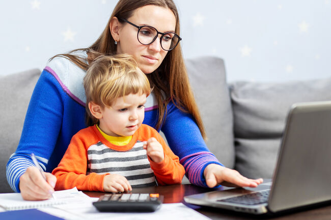 Young woman working at home with a laptop with a child on her lap