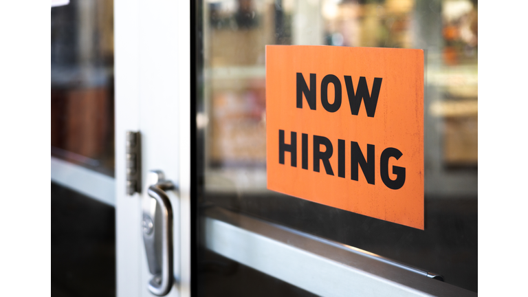 “now hiring” sign posted on business door