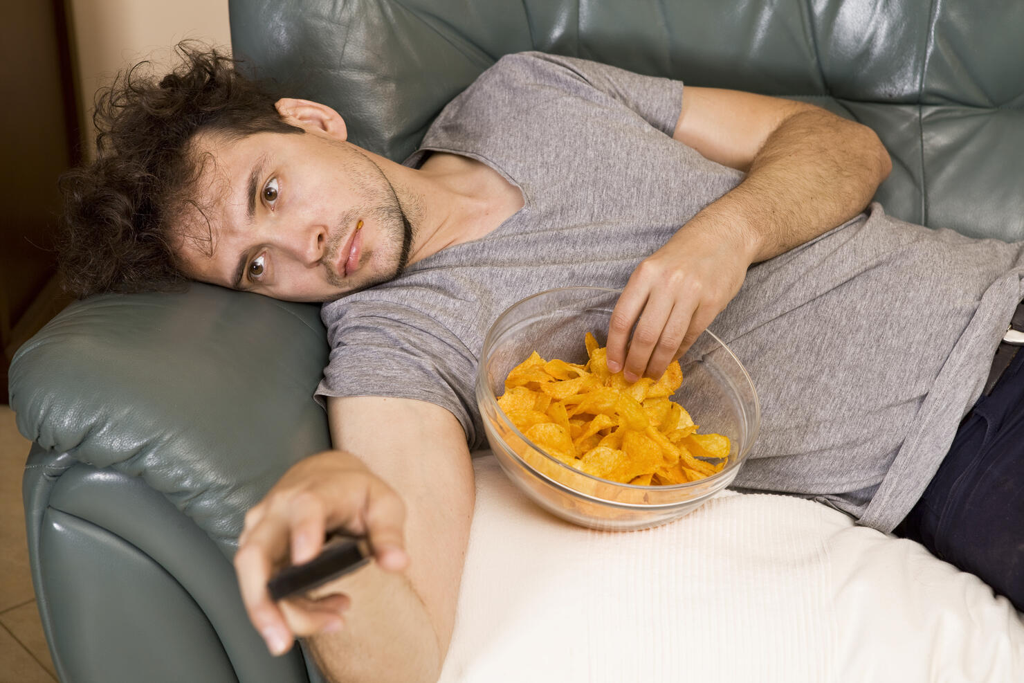 Lazy man with the remote and chips on the couch