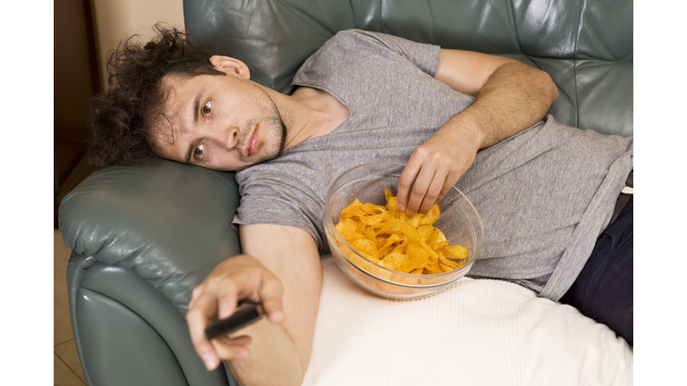 Lazy man with the remote and chips on the couch