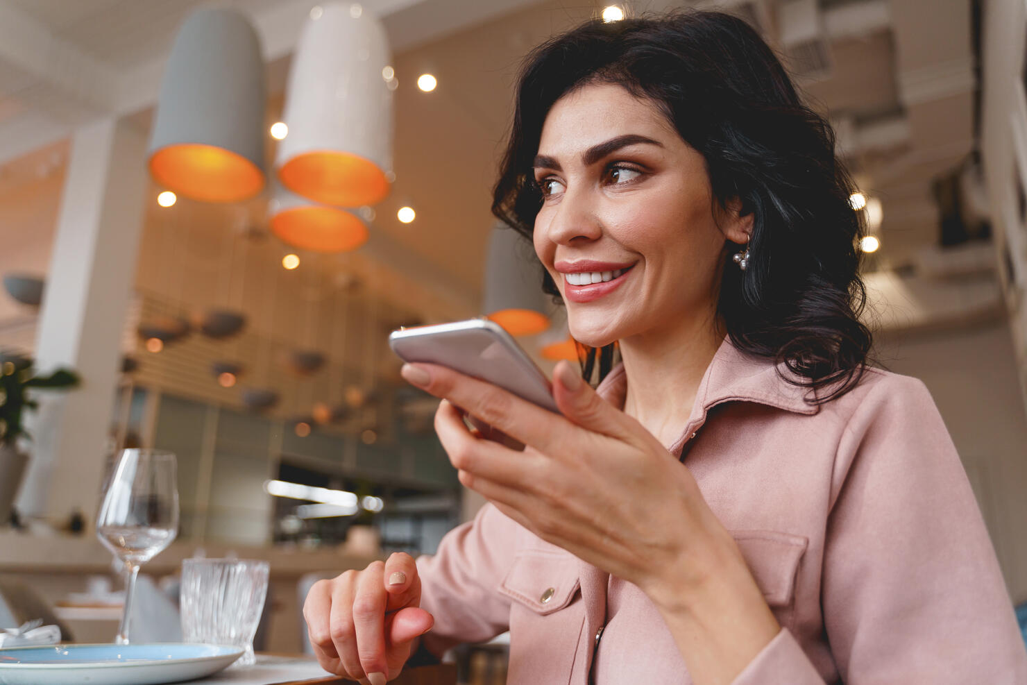 Joyful young woman talking on mobile phone in cafe