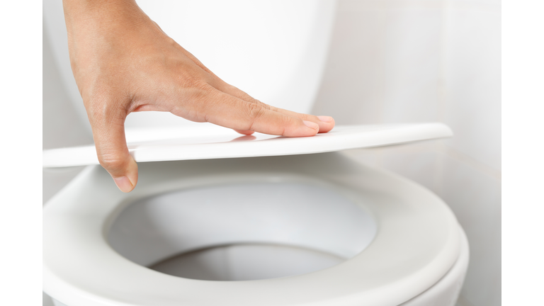 Womans hand opening the toilet lid
