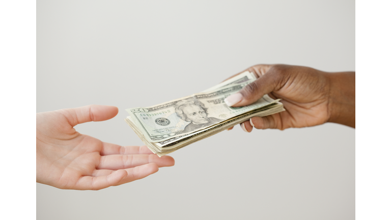 African woman handing over stack of 20 dollar bills