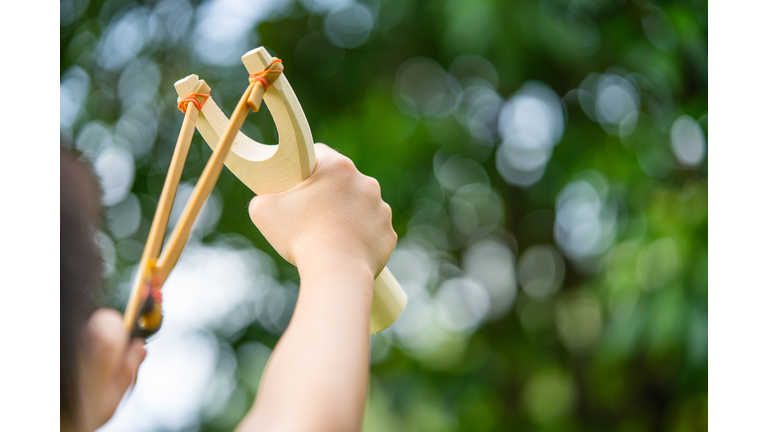 A boy shoots a slingshot .