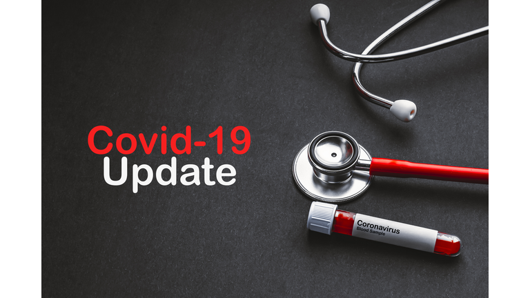 COVID-19 UPDATE text with stethoscope and blood sample vacuum tube on black background