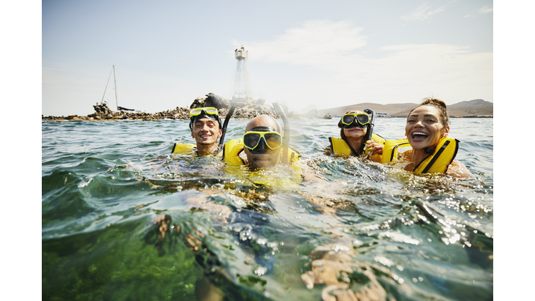 Medium shot of smiling family on snorkeling tour in tropical ocean