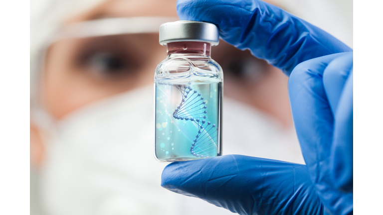 UK lab scientist biotechnologist holding glass ampoule vial with DNA strand