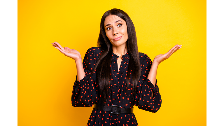 Photo of funny upset young woman wear dotted outfit arms not know answer isolated yellow color background