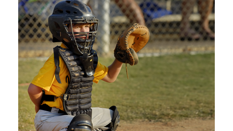 Young boy playing catcher in Youth League baseball game