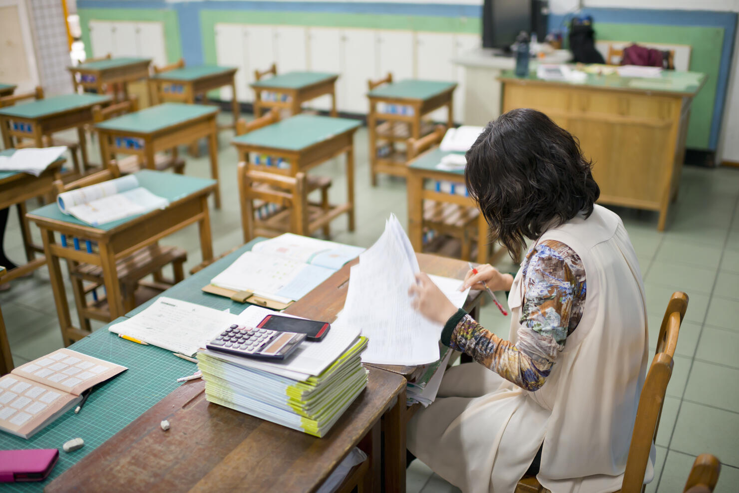 Teacher marks exam papers in classroom