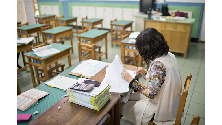 Teacher marks exam papers in classroom