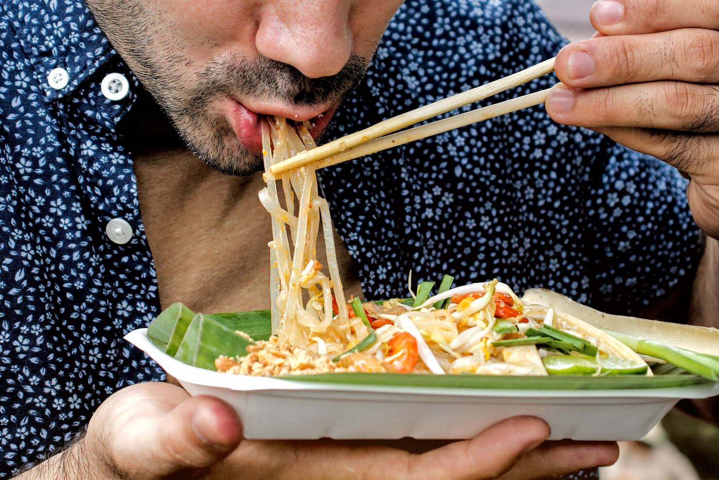 Tourists eating Pad Thai. Traditional street food in Thailand