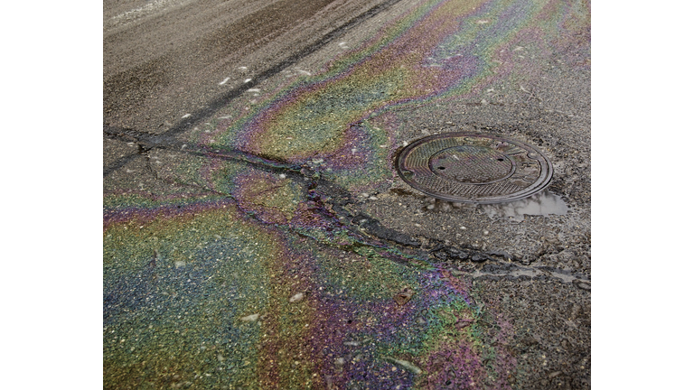 Oil on a wet, cracked road near a manhole