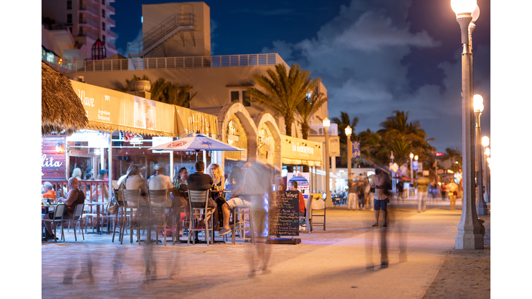 Tourism on Hollywood Beach FL night photo tourists sitting on tables eating and drinking