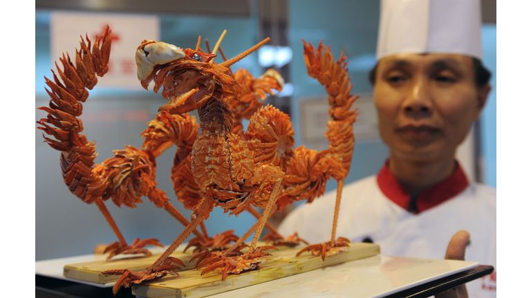 A chef displays two dragon-shaped dishes