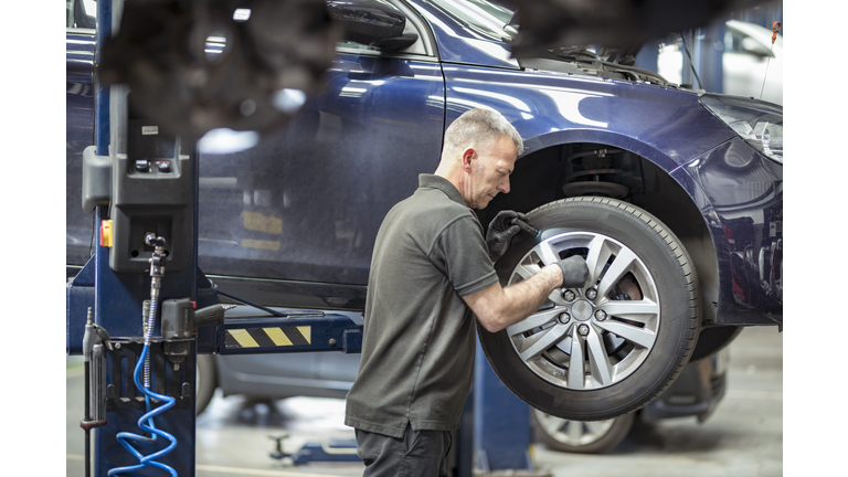 Engineer checking brakes in car service centre