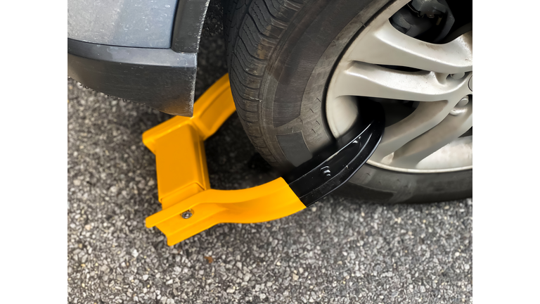 wheel clamp: bright orange immobilization device on front car wheel